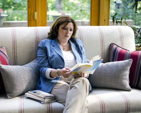 Dolly Ford-Sullivan, West Virginia Life Coach, on couch with book